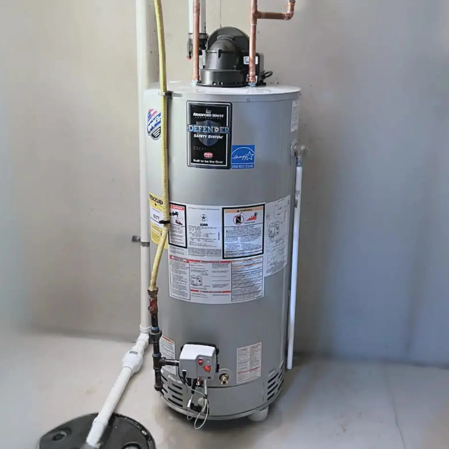 A standard residential water heater installed in a utility corner.