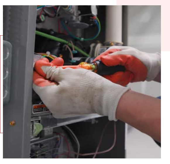 Technician repairing electrical components with tools and gloves.