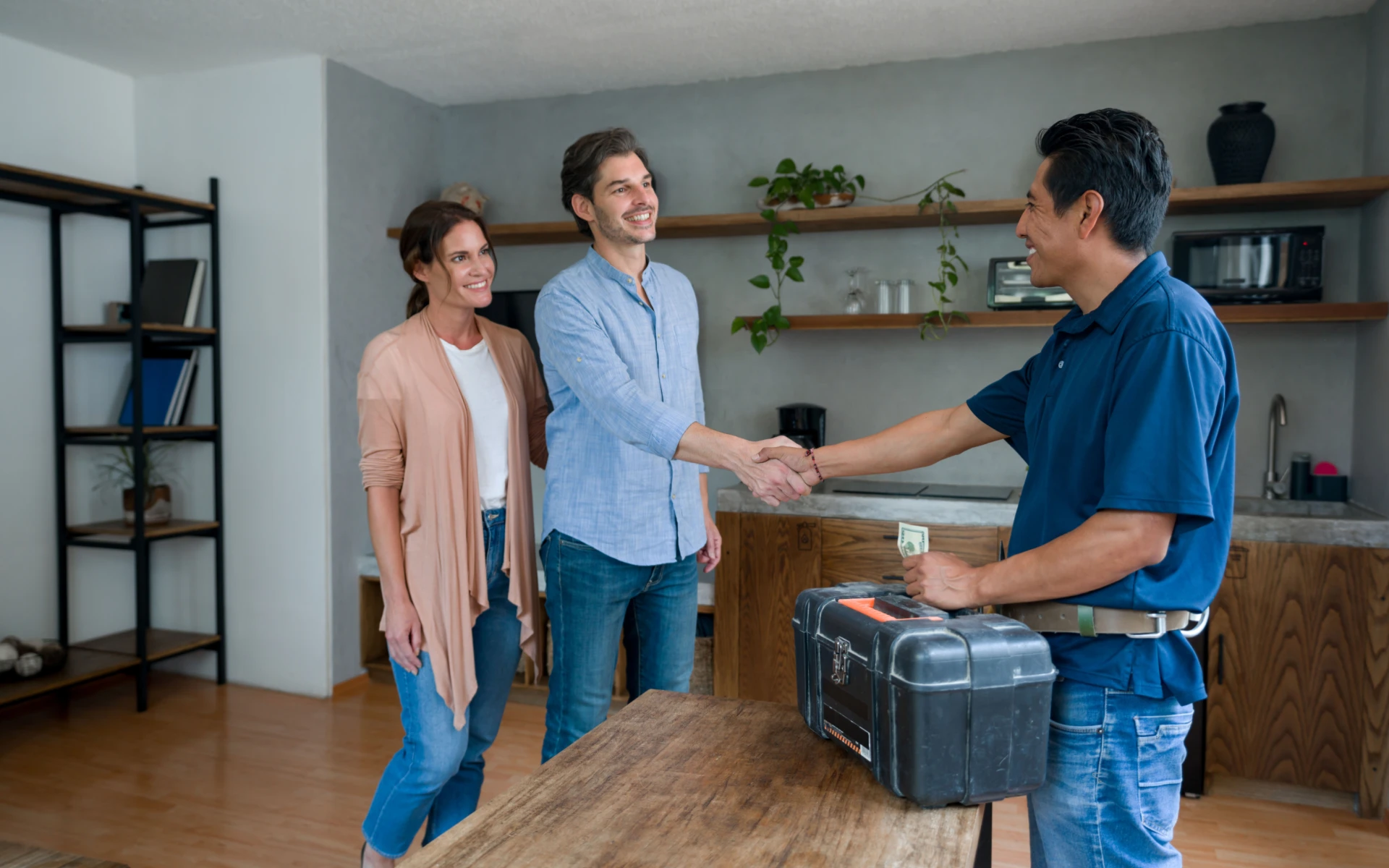 Couple shaking hands with handyman at home.
